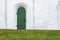 Closed green door in an old white stone wall