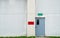 Closed grey door with green and red text box on white concrete wall