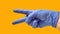 Closed hand with open thumb and index finger wearing a blue glove and yellow background. Victory concept