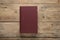 Closed hardcover book on wooden table, top view