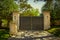 Closed impressive wrought iron luxury  security gate with key pad for private residential estate in leafy neighborhood with green