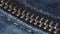 Closed metal zipper of jeans close-up. Blue denim fabric.