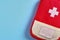 Closed red travel first aid kit pouch on the bright blue background. Photo with a copy space