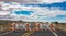 Closed road sign, street barriers and traffic cones on empty highway, cloudy sky background.  3d illustration