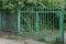 Closed rural metal gate made of green iron bars