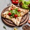 Closed star shaped pizza decorated with lettuce and cherry tomatoes