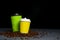 Closed take-out coffee with cup holder. Two yellow and green cups with coffee beans over black background.