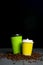 Closed take-out coffee with cup holder. Two yellow and green cups with coffee beans over black background.