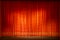 Closed theater curtain, red and gold, illuminated by devices.