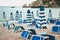 Closed umbrellas with blue and white lines and sunbeds on the beach