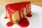 Closed up of baked cheesecake with vibrant red raspberry sauce served on white plate