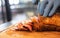 Closed up of chefâ€™s hand slicing grilled medium rare beef steak on wooden board Barbecue