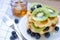 Closed up fresh sliced kiwi and blueberry fruit with honey on top of delicious homemade waffle in white dish