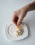 Closed up hand dipping Tuna spread in white plate with mini cracker.