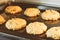 Closed up of hot baking oatmeal raisin cookies on black plate pan in the oven, using raisin and oat for main ingredient