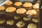 Closed up of hot baking oatmeal raisin cookies on black plate pan in the oven, using raisin and oat for main ingredient