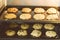 Closed up of hot baking oatmeal raisin cookies on black plate pan in the oven, using raisin and oat for main ingredient