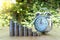 Closed up shot of alarm clock with Coin stacks on green background.