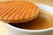 Closed up stroopwafel placed on top of the cup of hot coffee, selective focus