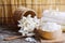 Closed up white spa salt in wooden bowl and spoon over blur soft white towel and fragrance flower