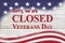 Closed Veterans Day sign with flag on wood