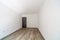 Closed wooden door in empty bright room. New home interior. Wooden floor. White walls