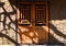 Closed wooden door with hanging door lock under sun rays