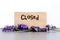 Closed - word burnt in wood with purple lavender flowers on slate with white background