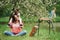 Closeness of the people. Mother and daughter sitting near easel in the park at spring time