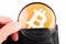 Closer look at bitcoin logo, symbol in a wallet, man examining BTC cryptocurrency, magnifying glass in hand. Cryptocurrency