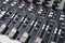 Closeup of a 16 channel digital stereo mixer - Focus on Channel faders and Aux knobs. Small recording studio setup