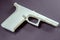 Closeup of 3D printed white "Ghost Gun" on a dark background.