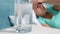 Closeup 4k footage of glass of water with dissolving aspirin medicament on bedside table against woman suffering from