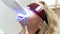 Closeup 4k video of blonde young woman lying in dentist chair during teeth whitening procedure