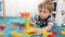 Closeup 4k video of happy smiling boy having fun while watching marble run made of colorful building blocks and bricks