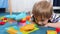 Closeup 4k video of little smiling boy lying on floor and looking at colorful marble ball rolling in marble run track