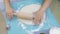 Closeup 5-year old girl rolls out raw dough with a small rolling pin on a silicone mat. Preparing dough for baking pizza