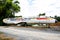 Closeup of abandoned damaged airplane beside the road with tree and sky background