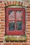 Closeup of abandoned red window covered in spiderwebs, algae and moss from neglect, poverty and economic crisis. Empty