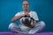 Closeup of an adult male in a white clothing practicing yoga and holding a Tibetan singing bowl