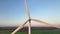 Closeup aerial footage of rotating blades of wind turbine with container ship on background and agricultural fields on eco farm mo