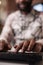 Closeup of african american coder writing software using computer keyboard while working remote