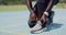 Closeup of an African female athlete tying shoe laces before jogging. Active fit woman ready and preparing to run on a