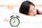 closeup alarm clock and beautiful asian young woman in morning,