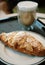 closeup almond croissant with hot coffee background