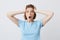 Closeup of amazed shocked young woman in blue t shirt standing with opened mouth and hands on her head isolated over white