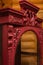 Closeup of ancient revived cupboard with handmade ornaments painted in red color with wooden house walls in background