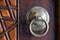 Closeup of antique copper ornate door knocker over an aged wooden door