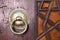 Closeup of antique copper ornate door knocker over an aged wooden door