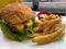 Closeup of an appetizing cheeseburger and french fries with a sauce, a serving of fast food